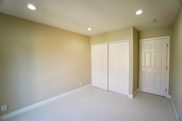 unfurnished bedroom with light carpet and a closet