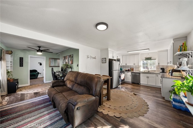 living room featuring a textured ceiling, dark hardwood / wood-style floors, ceiling fan, and sink