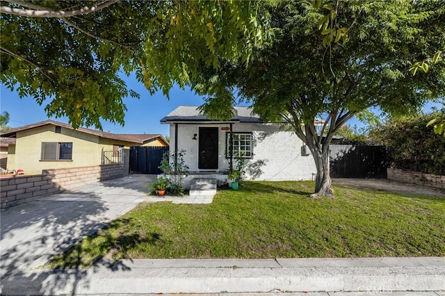 view of front of home featuring fence, a front lawn, and stucco siding