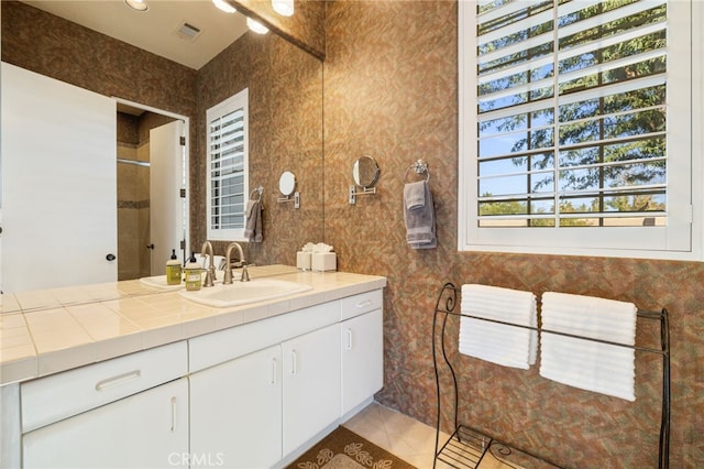 bathroom with tile patterned flooring, vanity, and tiled shower