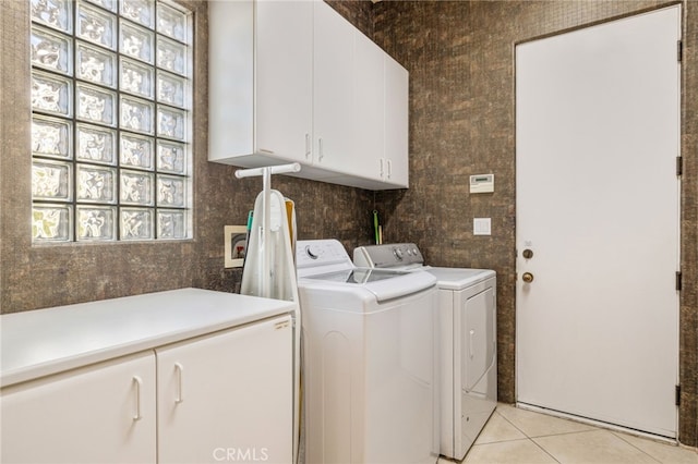 clothes washing area with independent washer and dryer, cabinets, and light tile patterned floors