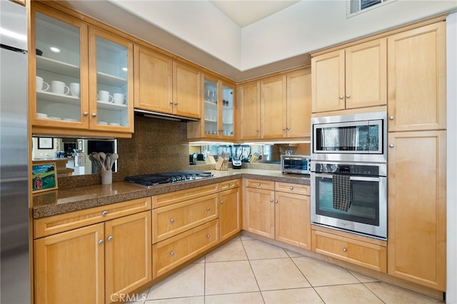 kitchen with extractor fan, appliances with stainless steel finishes, light tile patterned floors, and decorative backsplash