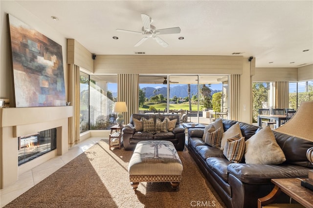 living room featuring light tile patterned flooring, ceiling fan, a healthy amount of sunlight, and a mountain view