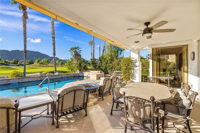 view of patio with ceiling fan, an outdoor fire pit, exterior bar, and a mountain view