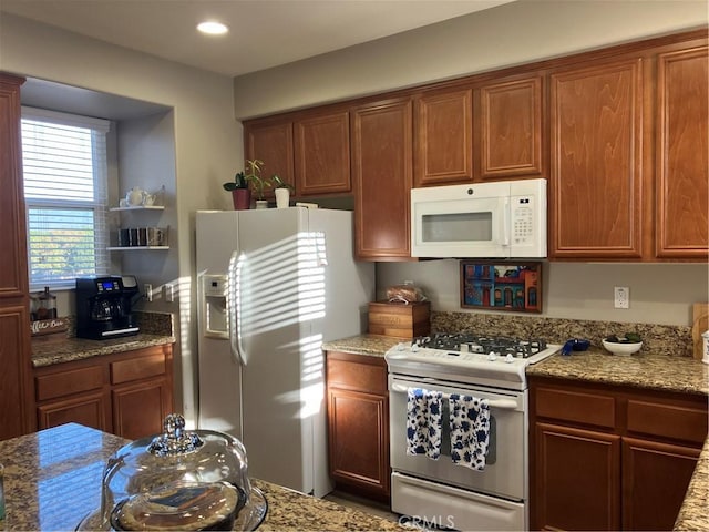 kitchen with light stone countertops and white appliances