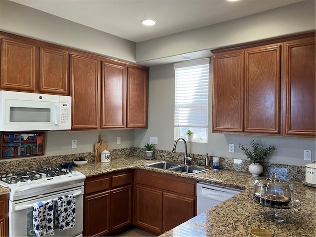 kitchen with stone counters, white appliances, and sink