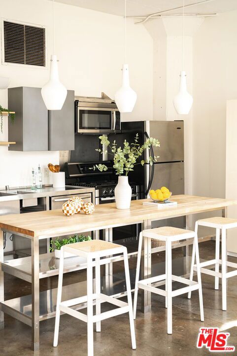 kitchen featuring butcher block counters, decorative backsplash, decorative light fixtures, and appliances with stainless steel finishes