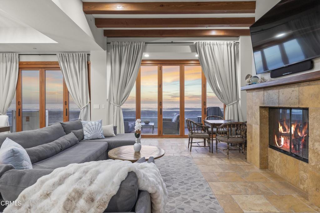 living room featuring beamed ceiling, a water view, and a fireplace