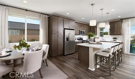 kitchen featuring pendant lighting, a wealth of natural light, dark brown cabinets, and stainless steel appliances