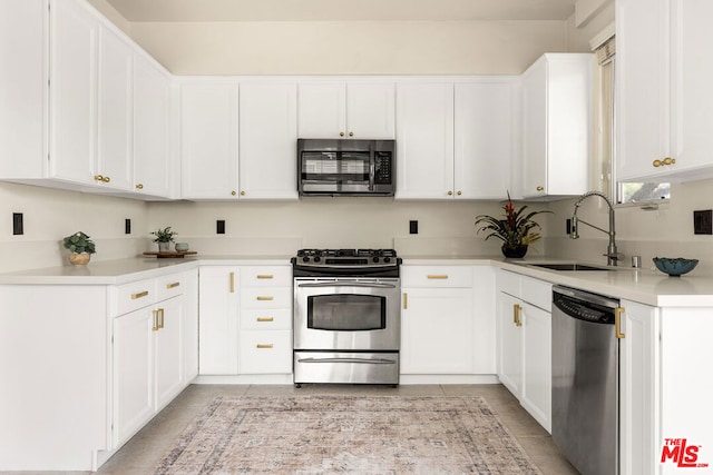 kitchen with light tile patterned floors, stainless steel appliances, white cabinetry, and sink