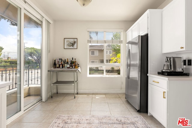 kitchen with light tile patterned floors, white cabinetry, and stainless steel refrigerator