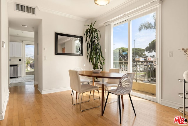 dining area with crown molding, light hardwood / wood-style flooring, and a healthy amount of sunlight