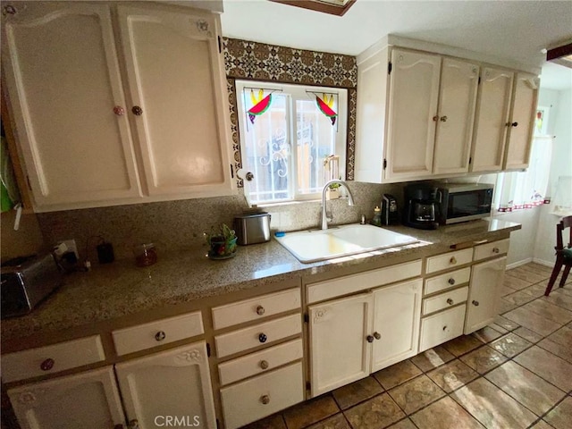 kitchen featuring decorative backsplash, light tile patterned floors, and sink