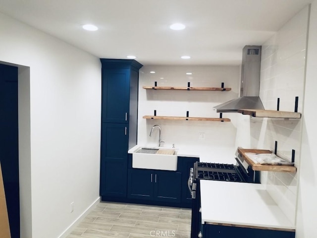 kitchen featuring blue cabinetry, gas range gas stove, sink, light hardwood / wood-style floors, and island range hood