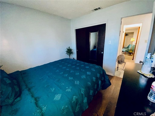 bedroom featuring a closet, a textured ceiling, and hardwood / wood-style flooring