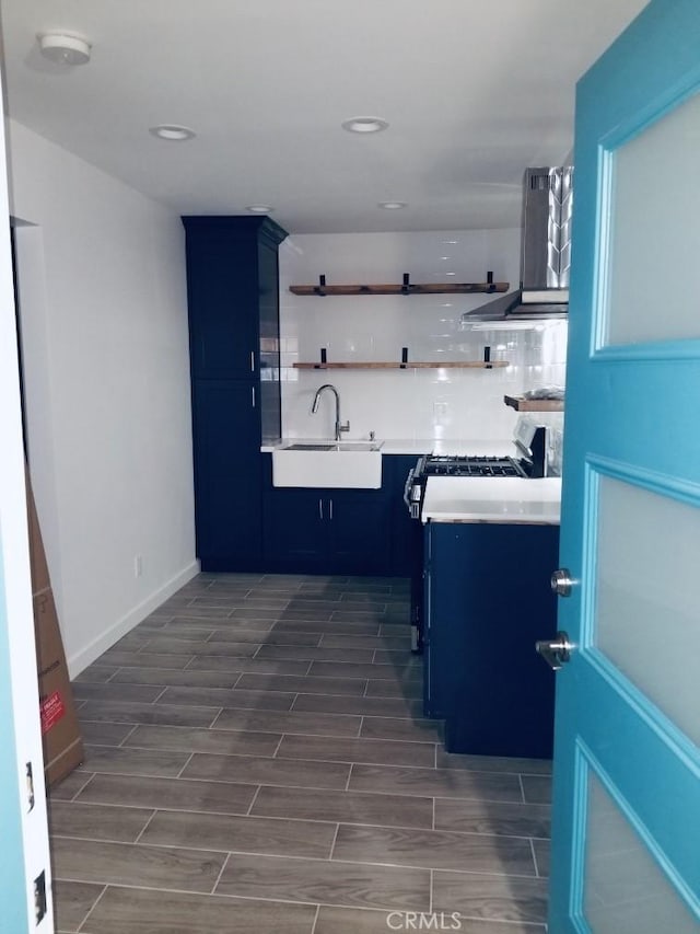 kitchen featuring blue cabinetry, backsplash, extractor fan, and sink