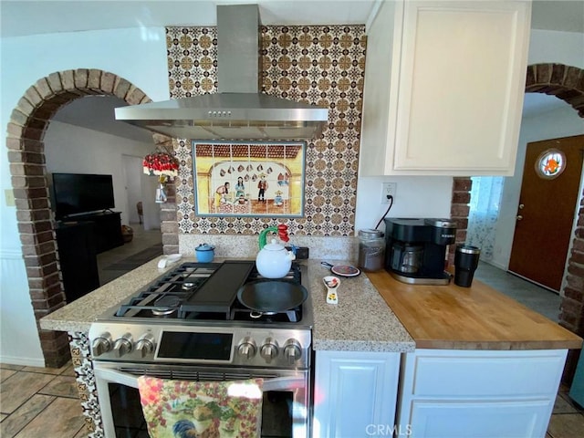 kitchen with white cabinetry, light stone counters, wall chimney range hood, and high end range