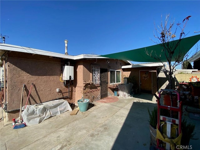 rear view of property featuring water heater and a patio