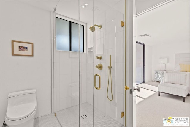 bathroom featuring a shower with shower door and toilet