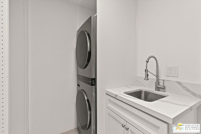 washroom featuring cabinets, stacked washer and clothes dryer, and sink