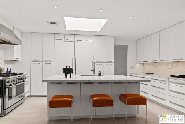 kitchen with high end appliances, sink, an island with sink, and a kitchen breakfast bar