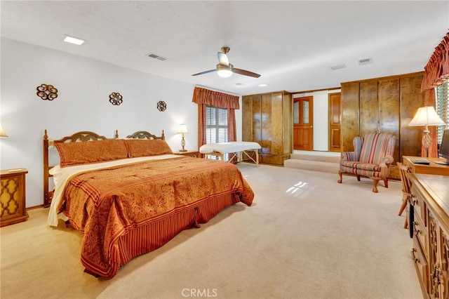 bedroom featuring ceiling fan, wood walls, and light colored carpet