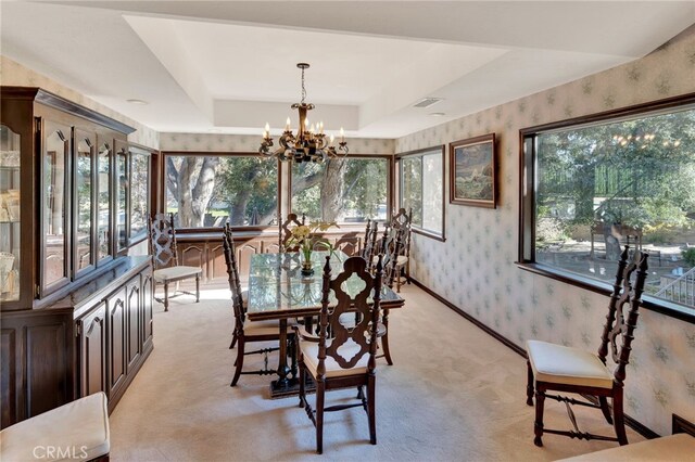 sunroom featuring a raised ceiling, a chandelier, and a healthy amount of sunlight