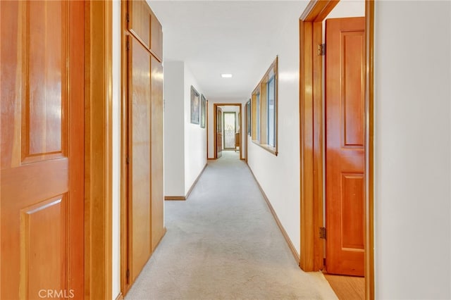 hall featuring light carpet and baseboards