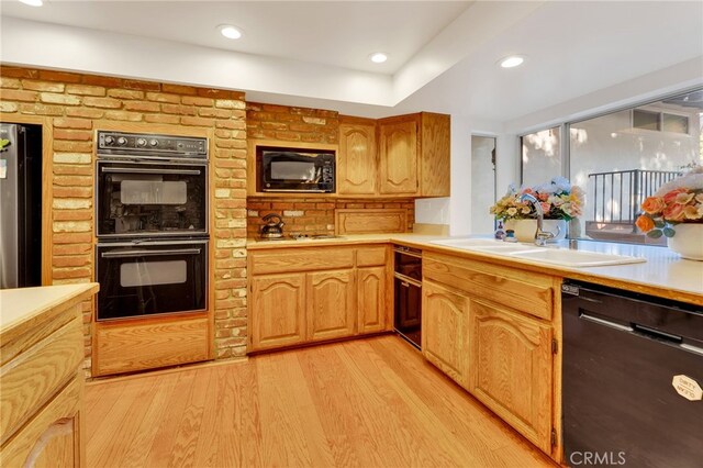 kitchen with sink, black appliances, and light hardwood / wood-style flooring