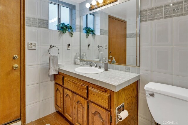 bathroom featuring vanity, tile patterned flooring, decorative backsplash, toilet, and tile walls