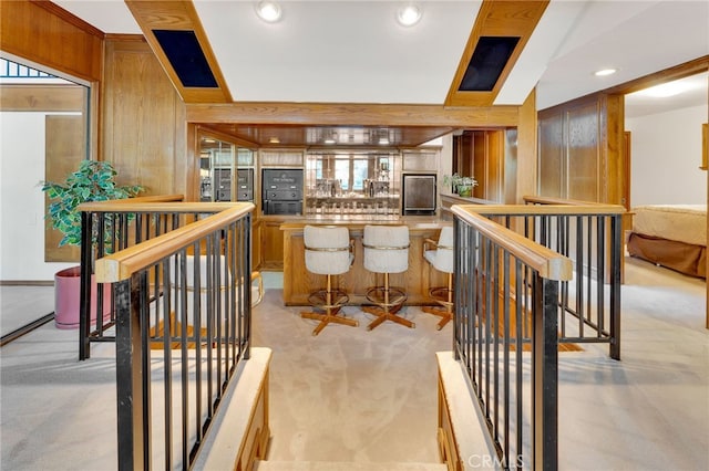 interior space with light colored carpet, plenty of natural light, and wooden walls