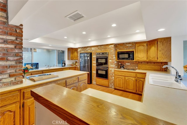 kitchen featuring light countertops, a sink, visible vents, and black appliances