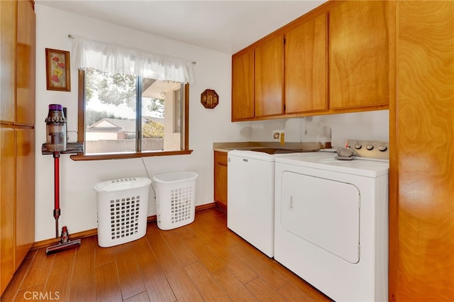 washroom with cabinets, light hardwood / wood-style flooring, and washer and clothes dryer