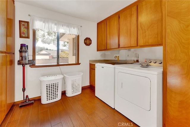 laundry room featuring cabinet space, independent washer and dryer, light wood-style flooring, and baseboards