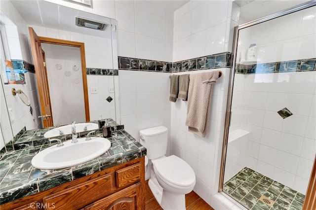 bathroom featuring an enclosed shower, vanity, wood-type flooring, tile walls, and toilet