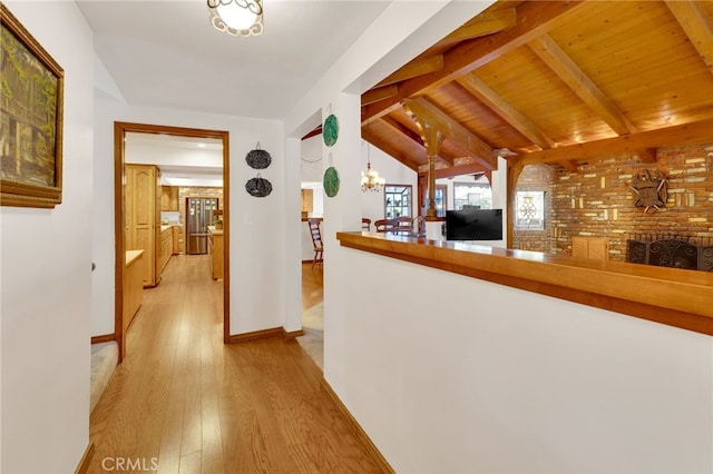 corridor with lofted ceiling with beams, wood ceiling, baseboards, light wood-style floors, and an inviting chandelier