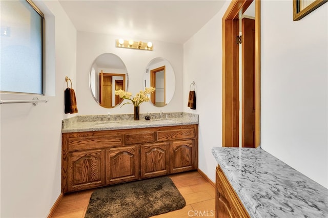 full bath with double vanity, baseboards, and a sink