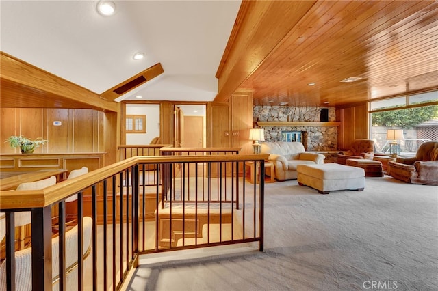 interior space with light carpet, wooden ceiling, wooden walls, and an upstairs landing