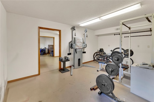 workout area with a textured ceiling, visible vents, and baseboards