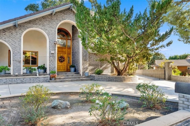 doorway to property featuring brick siding and a gate