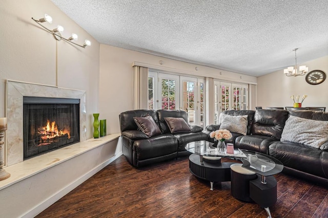 living room with french doors, a premium fireplace, dark hardwood / wood-style flooring, a notable chandelier, and a textured ceiling