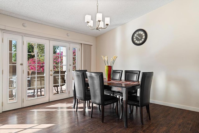 dining space featuring dark wood-type flooring, a textured ceiling, and a notable chandelier