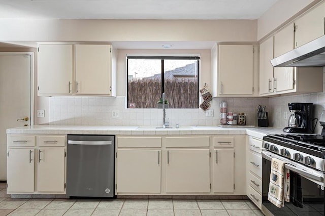 kitchen featuring backsplash, sink, light tile patterned flooring, and stainless steel appliances