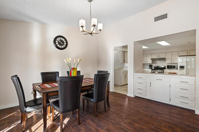 dining area with dark hardwood / wood-style flooring, a textured ceiling, and a chandelier