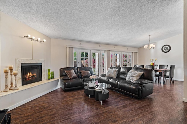 living room with french doors, dark hardwood / wood-style flooring, a chandelier, a textured ceiling, and a fireplace