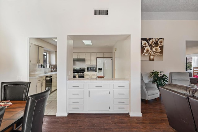 kitchen with dark hardwood / wood-style flooring, tasteful backsplash, a textured ceiling, stainless steel appliances, and sink