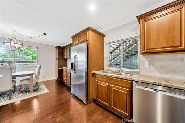 kitchen with sink, dark wood-type flooring, stainless steel appliances, a notable chandelier, and ornamental molding