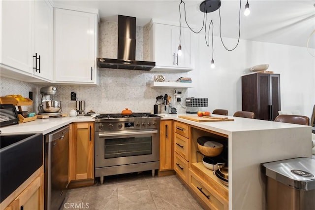 kitchen with pendant lighting, stainless steel appliances, white cabinetry, and wall chimney range hood