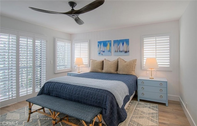 bedroom featuring access to exterior, light hardwood / wood-style flooring, multiple windows, and ceiling fan