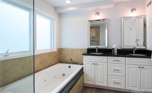 bathroom with vanity, a relaxing tiled tub, and wood-type flooring